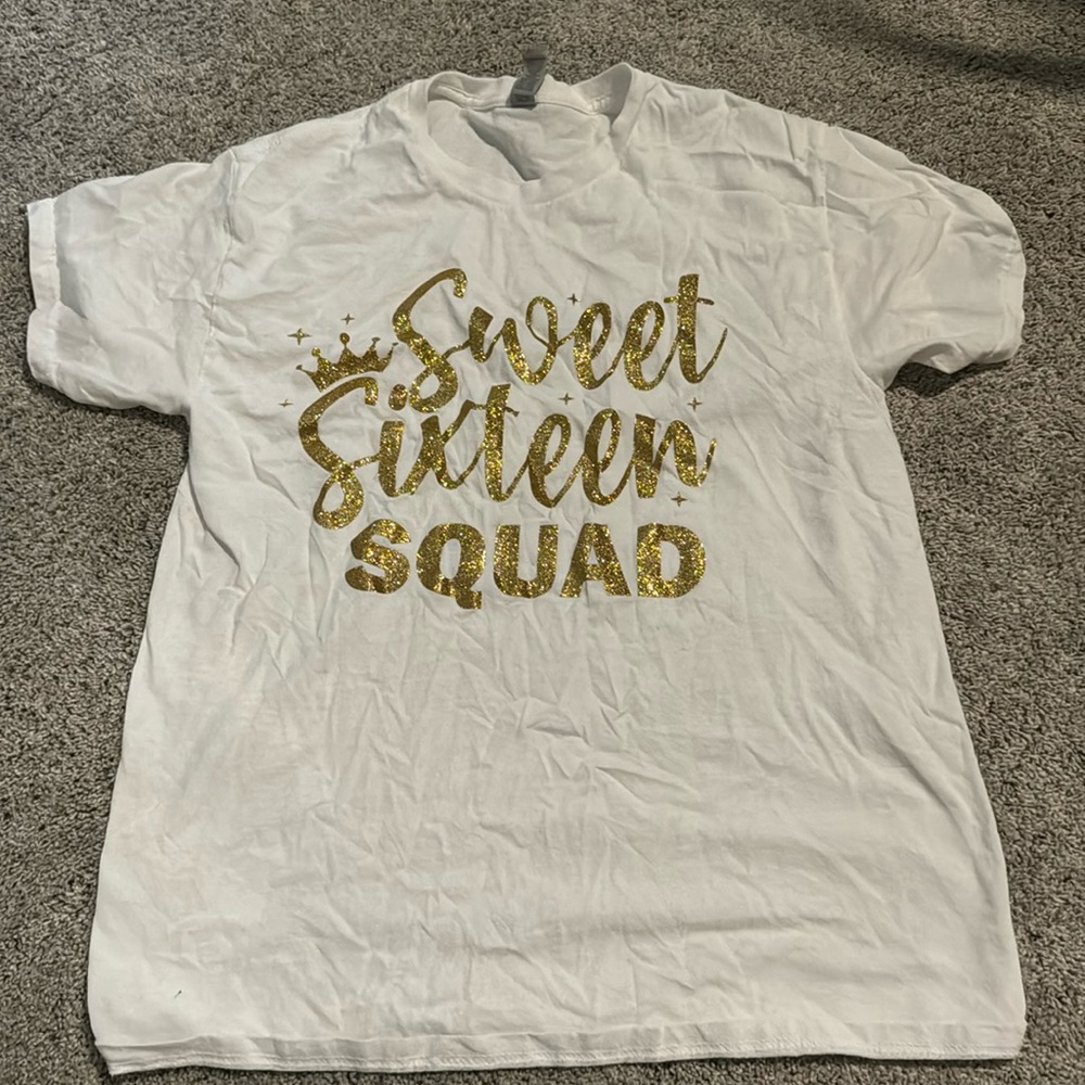 White t-shirt with gold cursive writing "sweet sixteen squad" 
Medium